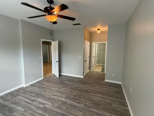 a view of empty room with wooden floor and fan