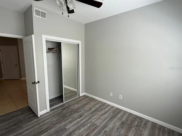 an empty room with wooden floor closet and windows