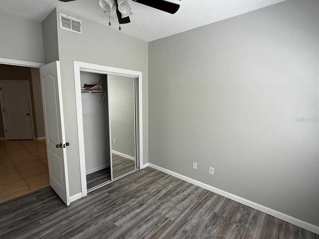 4817 Cypress Woods Drive, Unit 5203 Orlando, FL 32811 - Photo 18 of 22 an empty room with wooden floor closet and windows