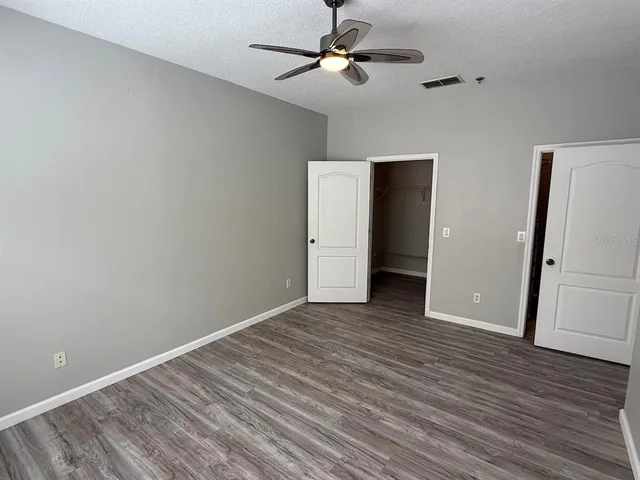 an empty room with wooden floor and ceiling fan