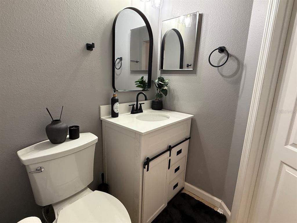 4817 Cypress Woods Drive, Unit 5203 Orlando, FL 32811 - Photo 22 of 22 a bathroom with a toilet sink and mirror