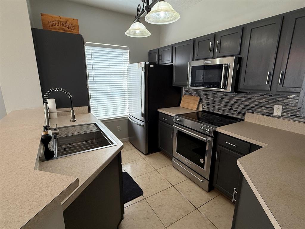 4817 Cypress Woods Drive, Unit 5203 Orlando, FL 32811 - Photo 7 of 22 a kitchen with a stove and a microwave