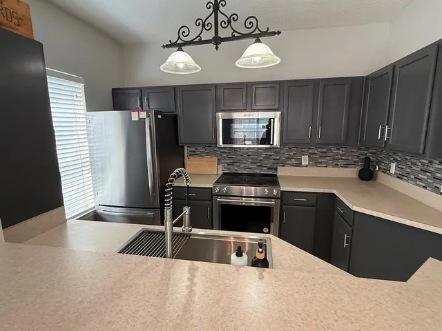 a kitchen with a refrigerator a stove a sink and dishwasher with wooden floor