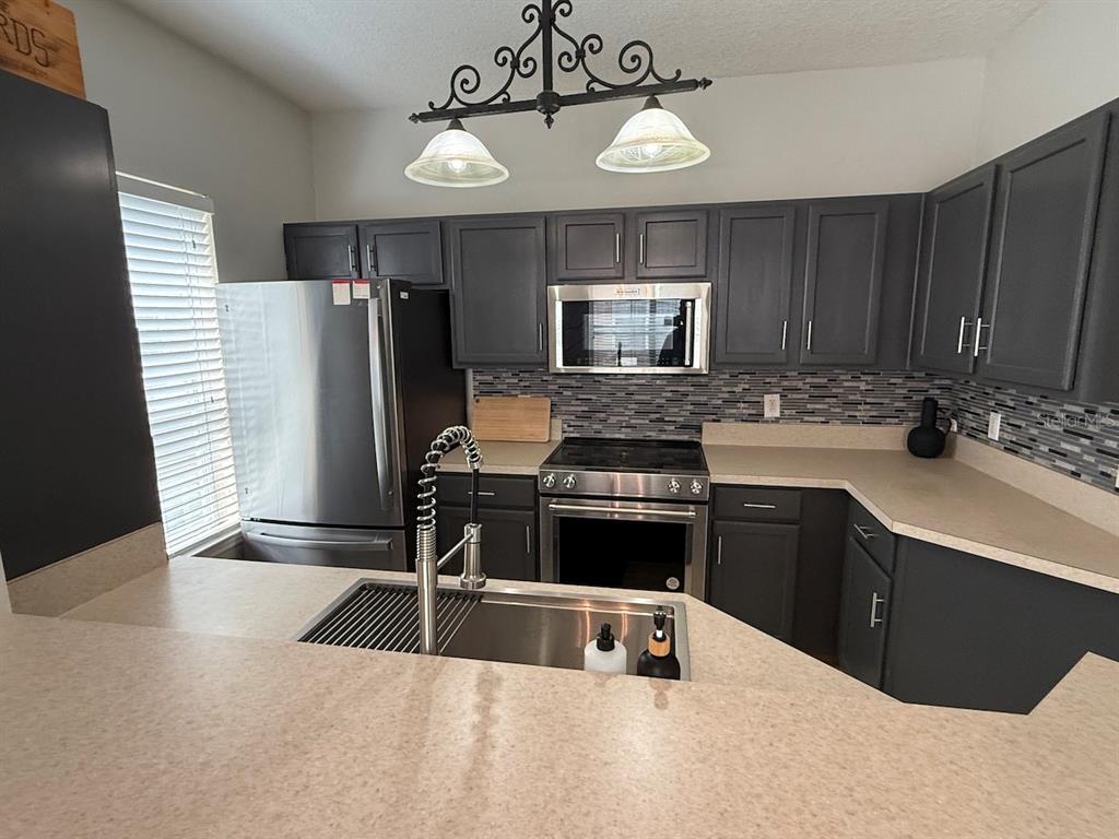 4817 Cypress Woods Drive, Unit 5203 Orlando, FL 32811 - Photo 8 of 22 a kitchen with a refrigerator a stove a sink and dishwasher with wooden floor