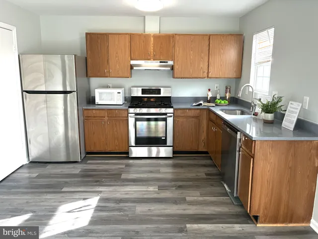 a kitchen with granite countertop a refrigerator and a stove top oven
