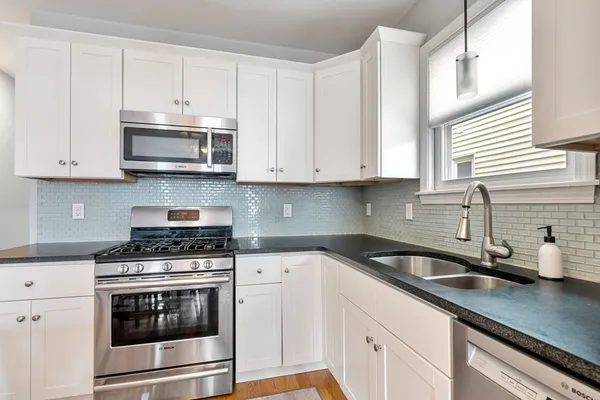 a kitchen with granite countertop white cabinets and stainless steel appliances