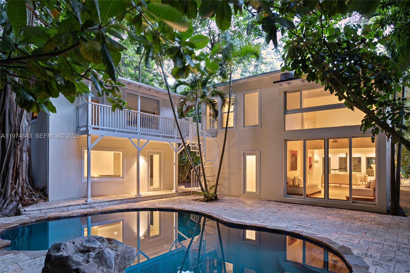 4286 Douglas Road Miami, FL 33133 - Photo 4 of 51 a view of a brick house with large windows and a tree