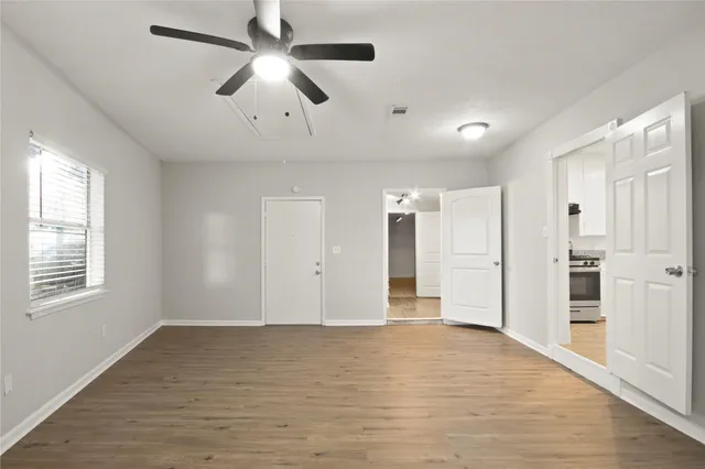 a view of an empty room with wooden floor and a window