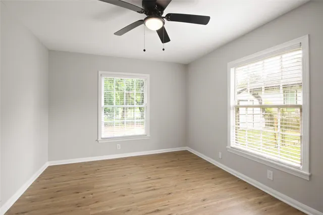 a view of an empty room with wooden floor and a window