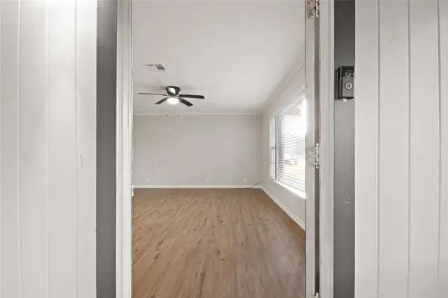 a view of a room with wooden floor a ceiling fan