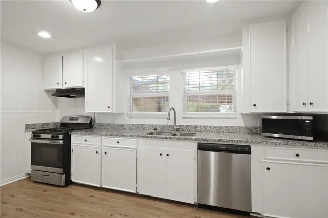 a kitchen with granite countertop a stove a sink and a microwave