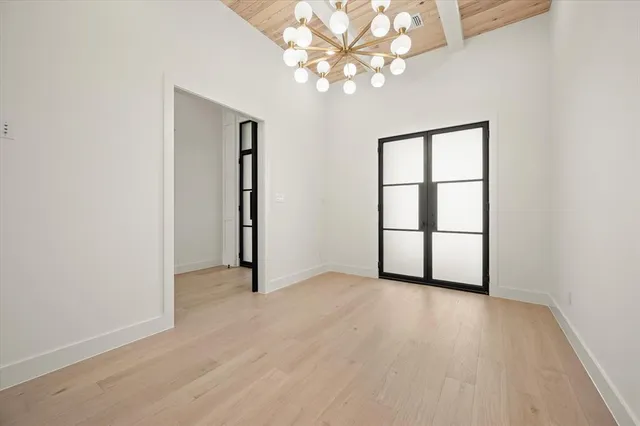 an empty room with chandelier fan and windows