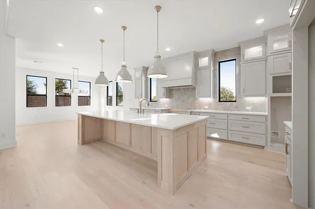 a large kitchen with kitchen island a sink white cabinets and stainless steel appliances
