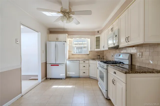 a kitchen with granite countertop a stove a sink a refrigerator and cabinets