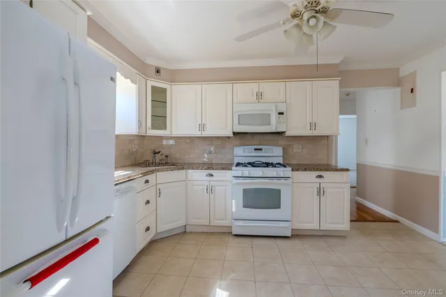 a kitchen with granite countertop white cabinets and white appliances