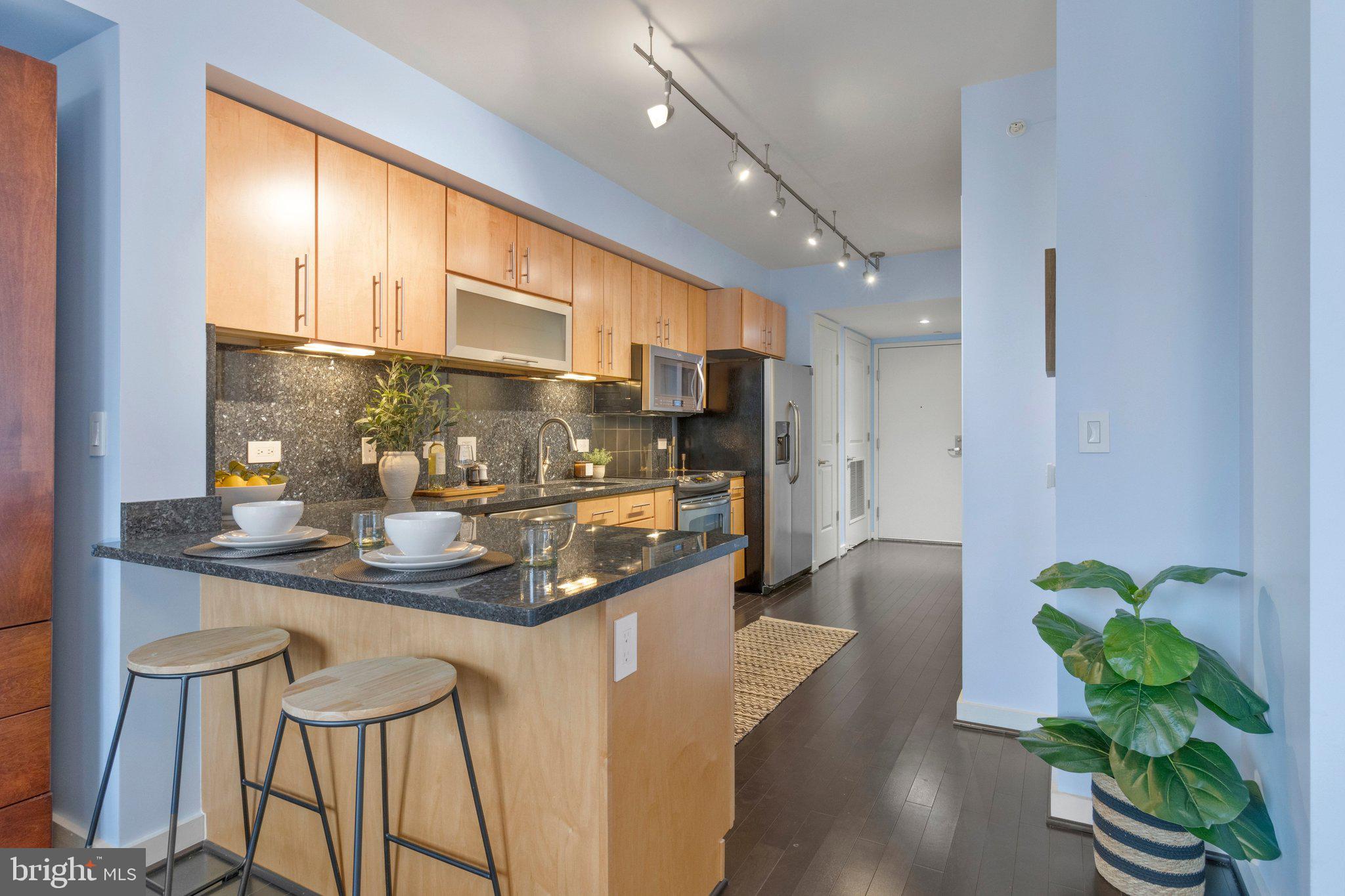 1025 First Street Southeast, Unit 907 Washington, DC 20003 - Photo 3 of 22 a kitchen with stainless steel appliances granite countertop sink stove and white cabinets with wooden floor