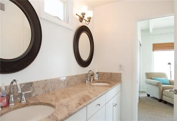 a bathroom with a granite countertop double vanity sink and a mirror
