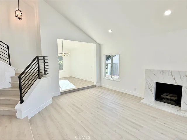 a view of an empty room with wooden floor and a fireplace