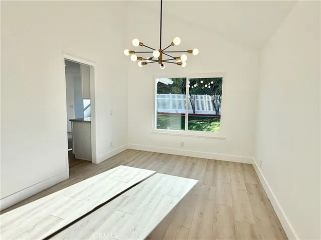 a kitchen with stainless steel appliances kitchen island granite countertop a refrigerator a sink a dining table and chairs with wooden floor