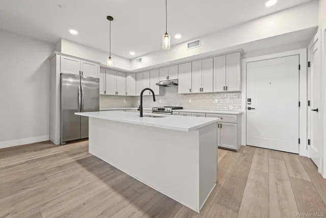 a kitchen with a sink stainless steel appliances and white cabinets