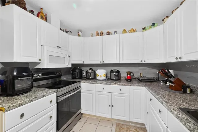 a kitchen with granite countertop white cabinets and white appliances