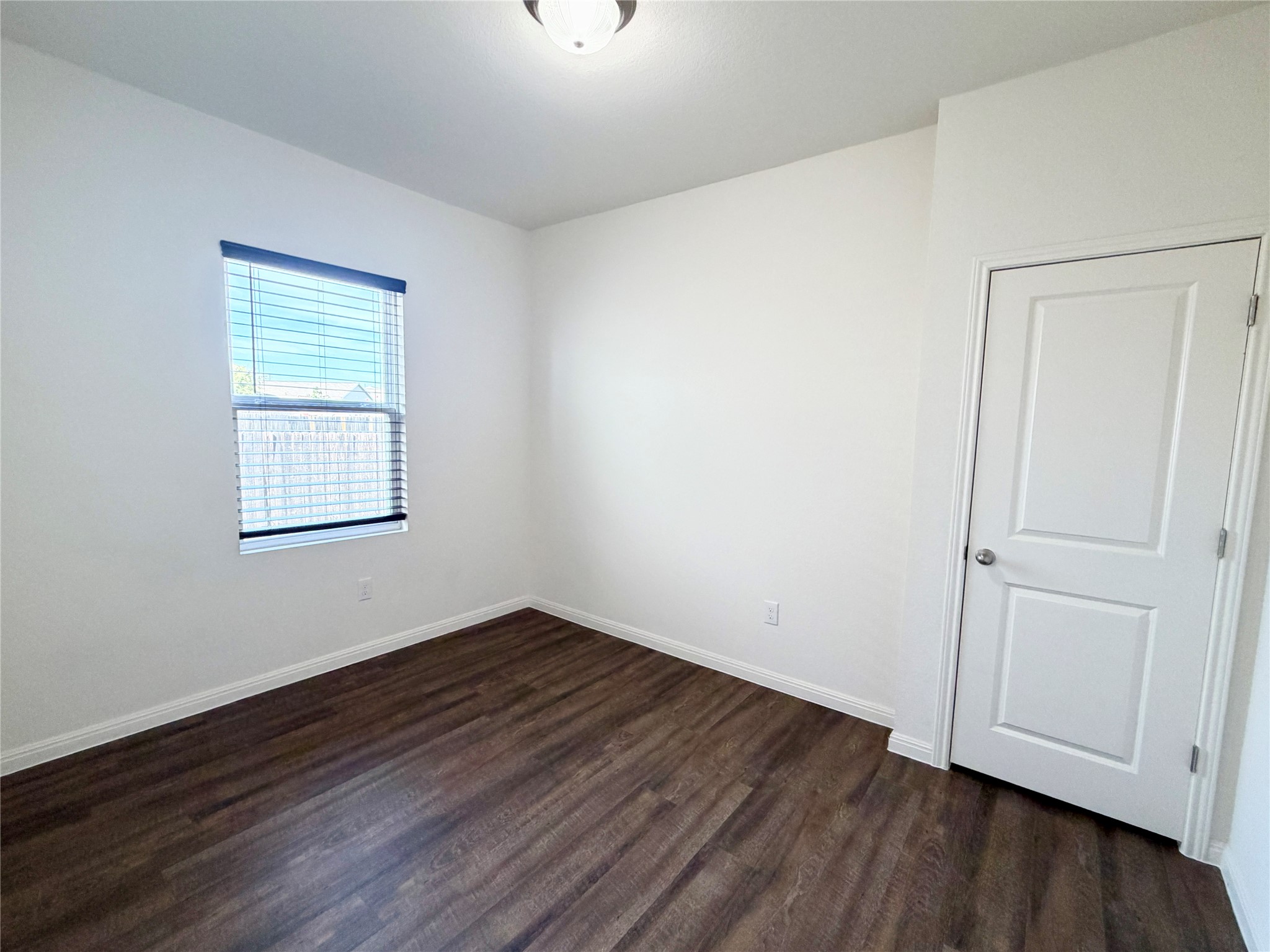 360 Bell Rings Drive Jarrell, TX 76537 - Photo 4 of 10 A quiet, naturally illuminated bedroom offers rich wood flooring and a classic white door.