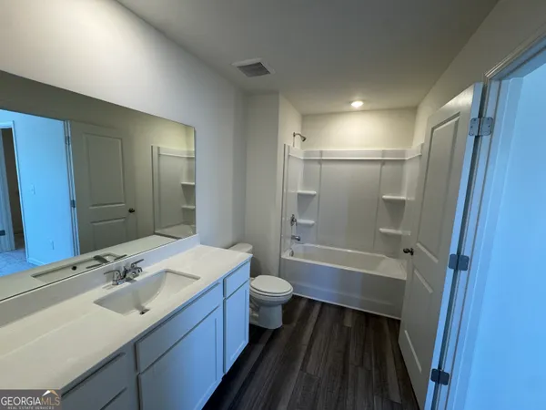 a bathroom with a sink a toilet a mirror and shower