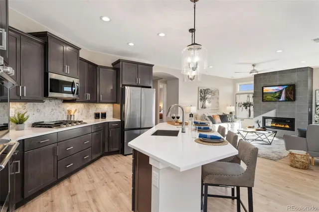 a kitchen with stainless steel appliances kitchen island granite countertop a sink dishwasher a stove a refrigerator with island and chairs