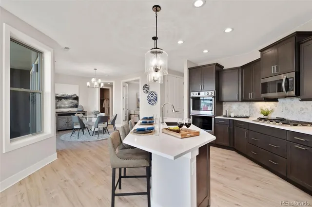 a kitchen with stainless steel appliances kitchen island granite countertop a sink dishwasher a stove a refrigerator with island and chairs