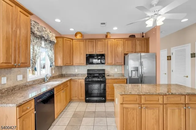 a kitchen with kitchen island granite countertop a sink stainless steel appliances and cabinets