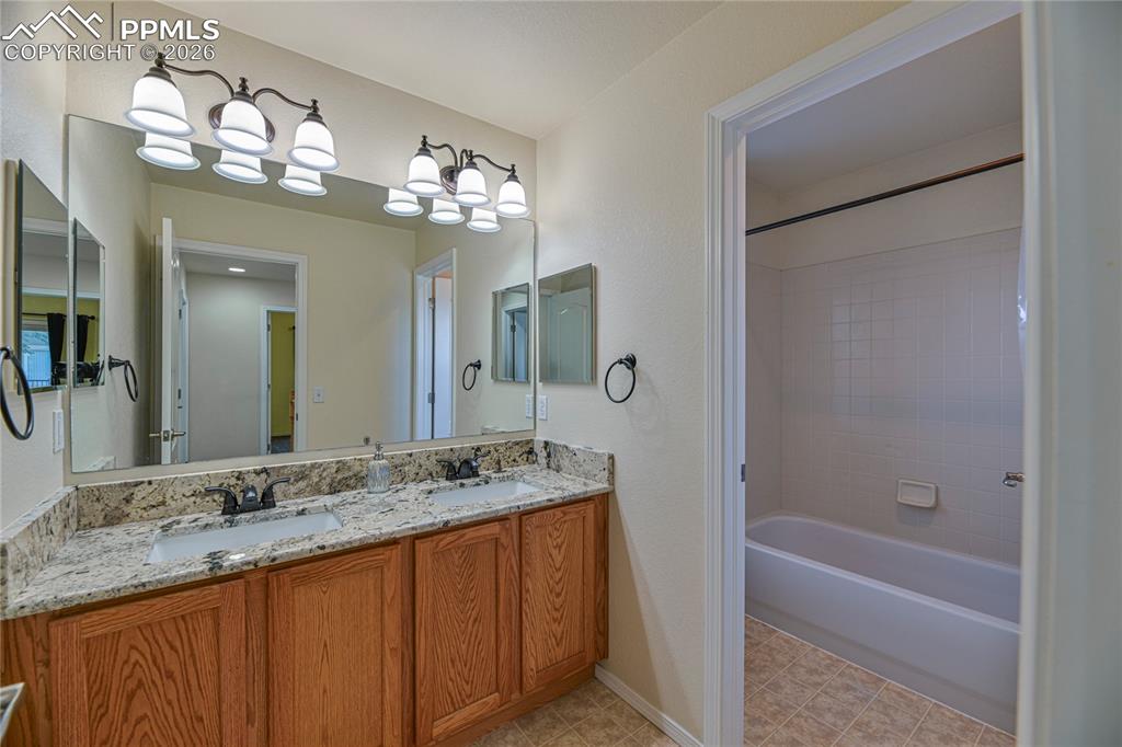 6432 Crystal Mountain Road Colorado Springs, CO 80923 - Photo 23 of 31 a bathroom with a granite countertop sink a large mirror and a bathtub