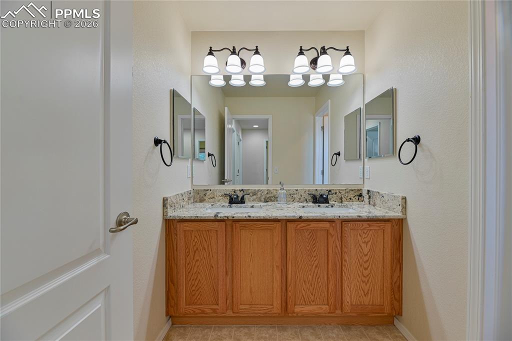 6432 Crystal Mountain Road Colorado Springs, CO 80923 - Photo 24 of 31 a bathroom with a granite countertop sink a large mirror and a shower