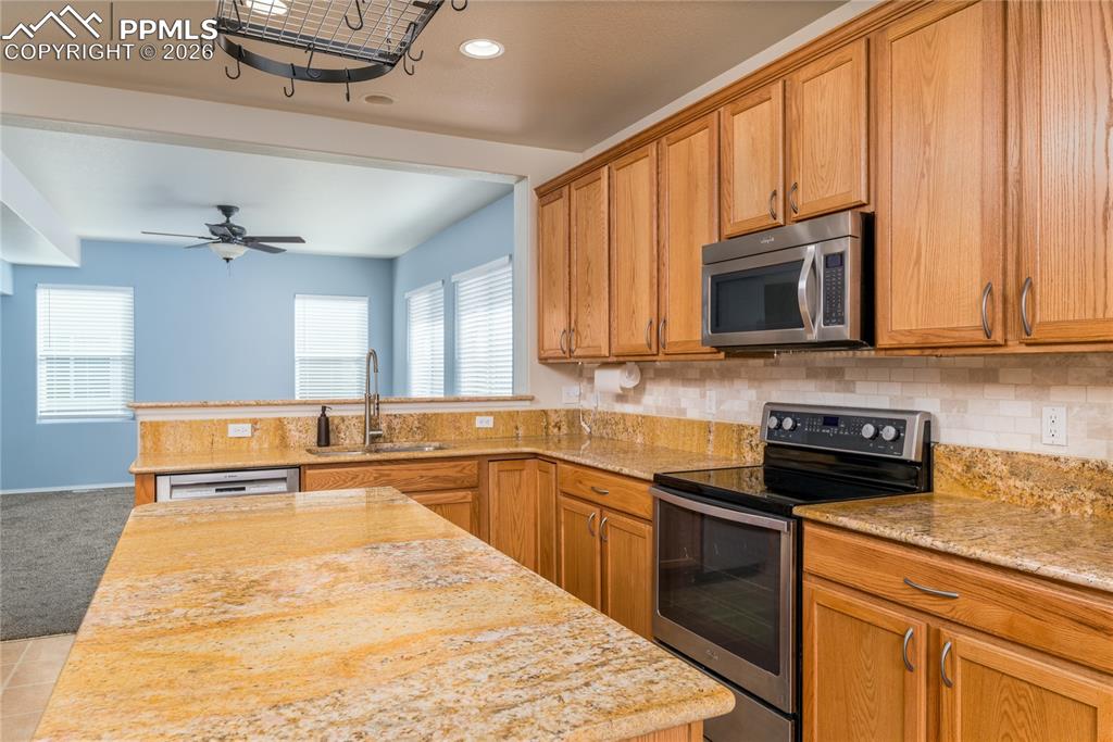 6432 Crystal Mountain Road Colorado Springs, CO 80923 - Photo 3 of 31 a kitchen with stainless steel appliances granite countertop wooden cabinets a stove top oven a sink and dishwasher