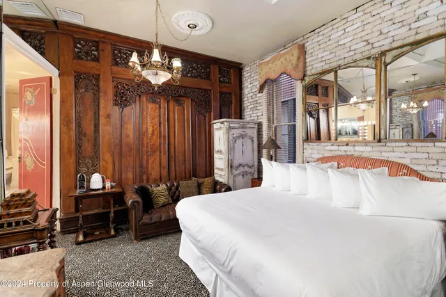 a bed room with a bed mirror and a chandelier