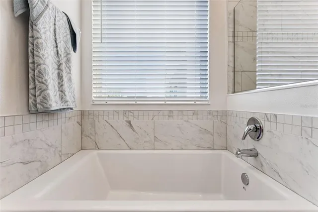 a white bath tub sitting in a bathroom next to a window