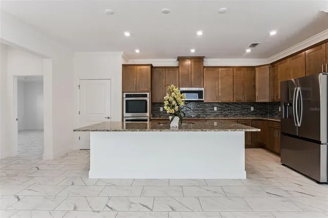 a large kitchen with stainless steel appliances a refrigerator and a stove