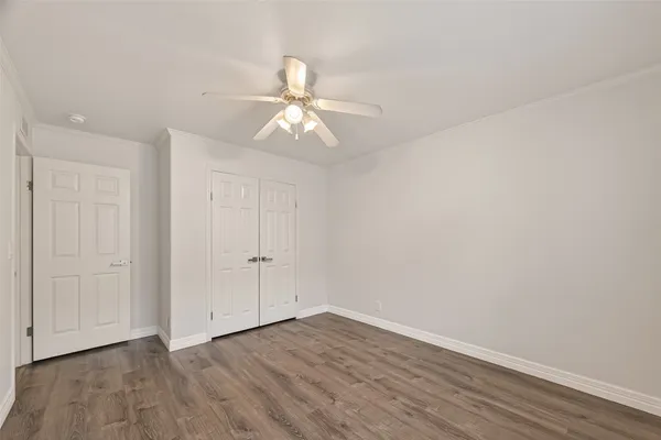 an empty room with wooden floor and ceiling fan