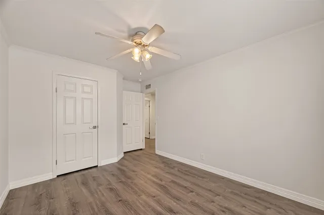 an empty room with wooden floor fan and windows
