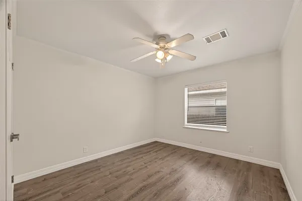 an empty room with wooden floor fan and windows