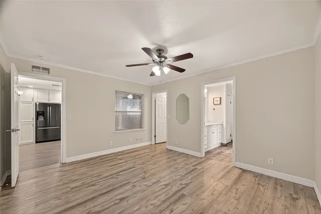 an empty room with wooden floor and a ceiling fan