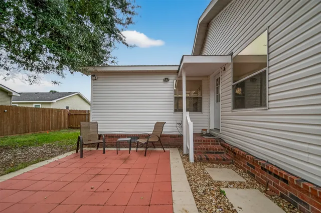 a backyard of a house with wooden fence and large trees