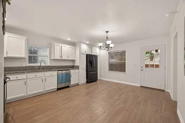 a large kitchen with granite countertop a stove top oven a sink dishwasher a dining table and chairs with wooden floor