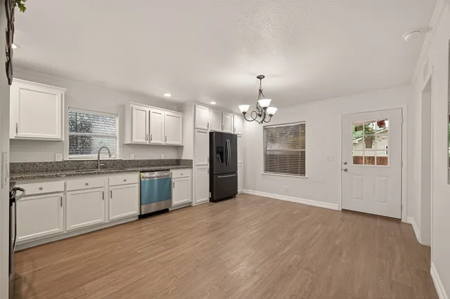 a large kitchen with granite countertop a stove top oven a sink dishwasher a dining table and chairs with wooden floor