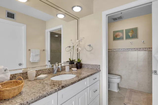 a bathroom with a granite countertop sink a toilet and a mirror