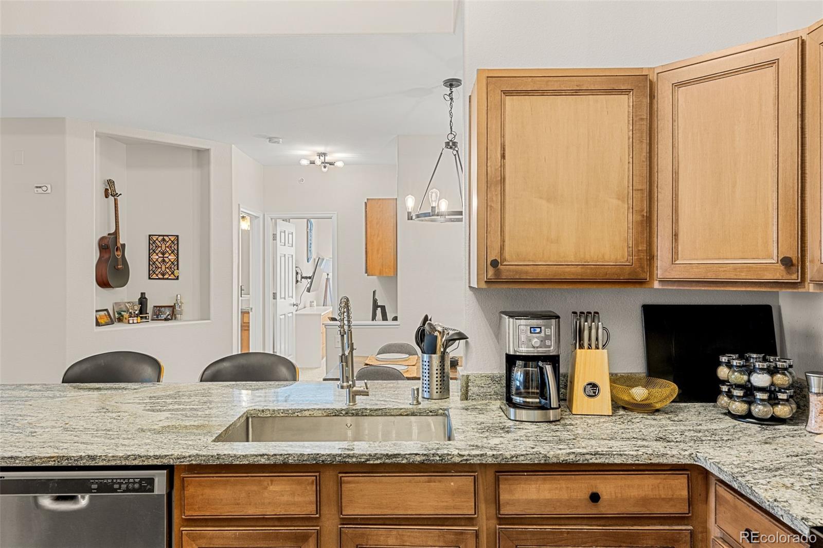 8073 West 51st Place, Unit 303 Arvada, CO 80002 - Photo 14 of 48 a kitchen with granite countertop a sink a stove and cabinets