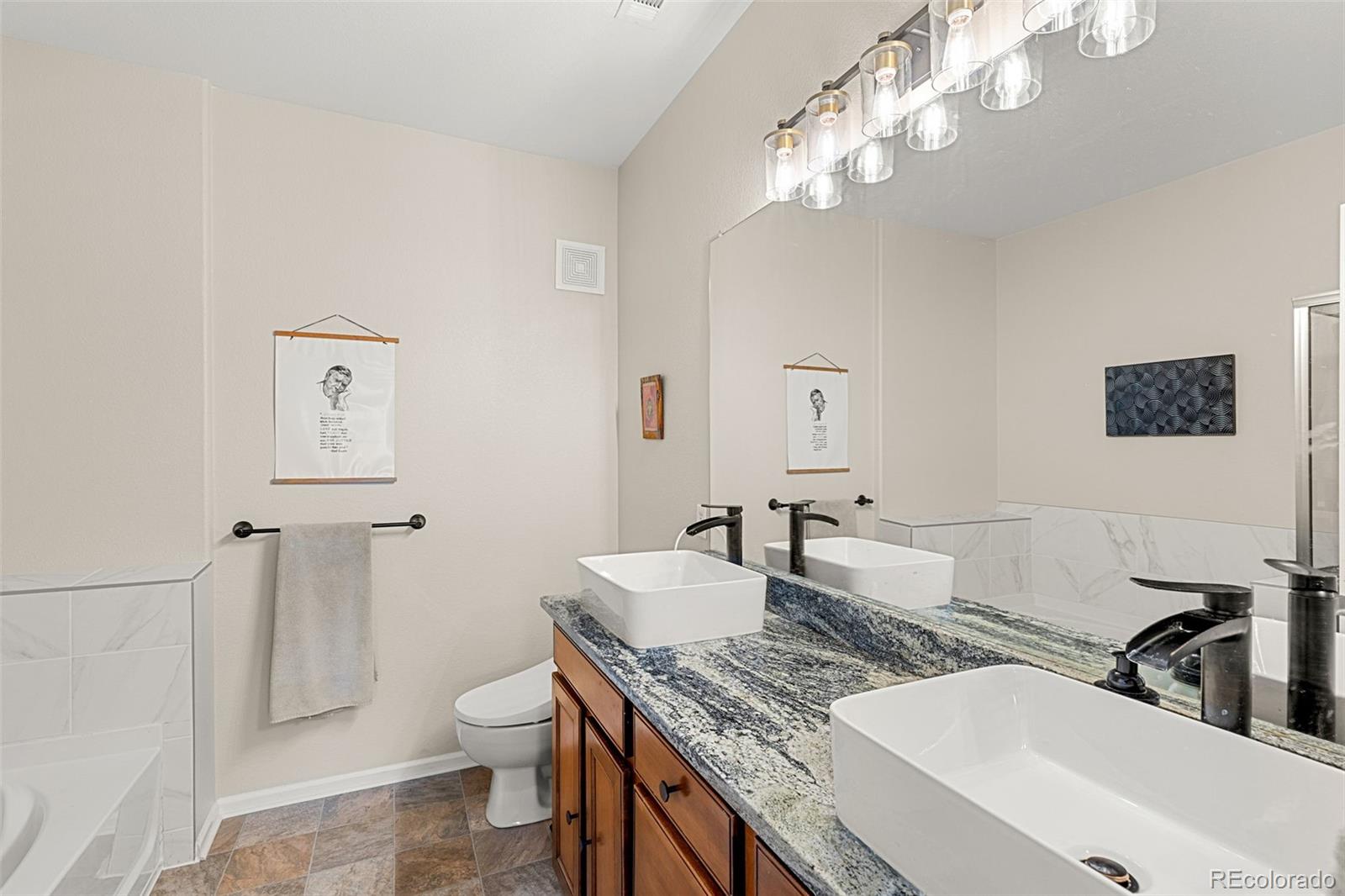 8073 West 51st Place, Unit 303 Arvada, CO 80002 - Photo 29 of 48 a bathroom with a granite countertop toilet a sink and mirror