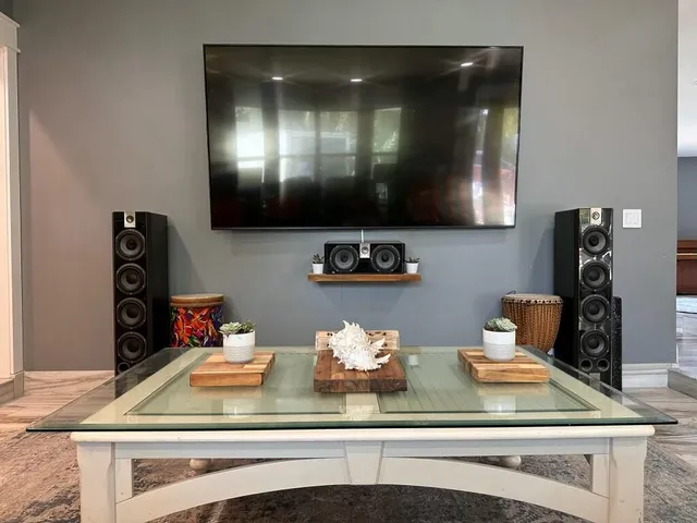 a kitchen with stainless steel appliances granite countertop a sink a stove a refrigerator cabinets and a dining table with wooden floor