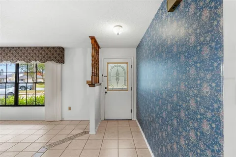a view of an empty room with window and chandelier fan