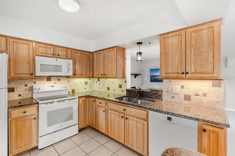 a kitchen with granite countertop stainless steel appliances white cabinets and a sink