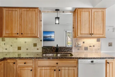 a kitchen with stainless steel appliances granite countertop a sink stove refrigerator and white cabinets with wooden floor